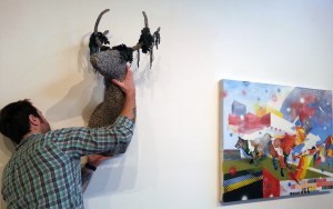 Grant Barber, UW Museuology Program Emerging Curator Initiative Gallery Intern, hangs Imaginature show